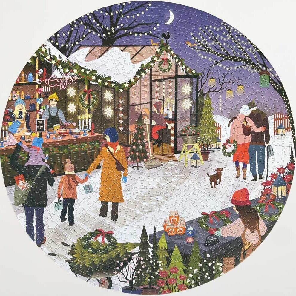 Ein rundes Puzzle mit einer Szene auf einem Weihnachtsmarkt. Menschen, darunter Erwachsene und Kinder, bewegen sich zwischen festlich dekorierten Ständen mit Weihnachtslichtern im Schnee. Ein Kaffee-Stand, Weihnachtsbäume, und weihnachtliche Dekorationen sind zu sehen. Im Hintergrund befinden sich ein verschneites Dach und ein lila-gefärbter Nachthimmel mit einem Halbmond.