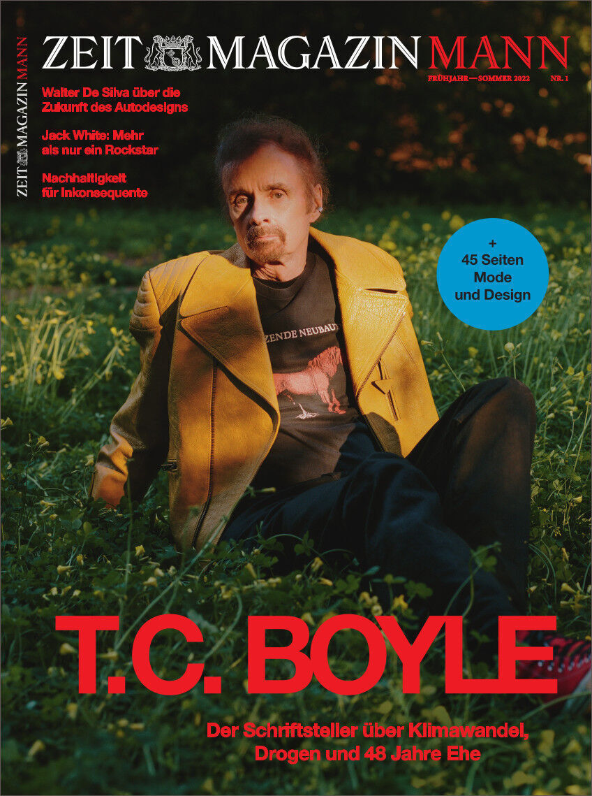Das Cover des ZEITmagazin MANN 1/22 zeigt ein Porträt von T.C. Boyle, der auf einer Wiese sitzt. Er trägt eine gelbe Jacke und ein schwarzes T-Shirt mit einem roten Aufdruck. Im Hintergrund ist grüne Vegetation zu sehen. Der Titel des Magazins sowie mehrere Artikelankündigungen sind in Weiß und Rot auf dem Cover platziert.