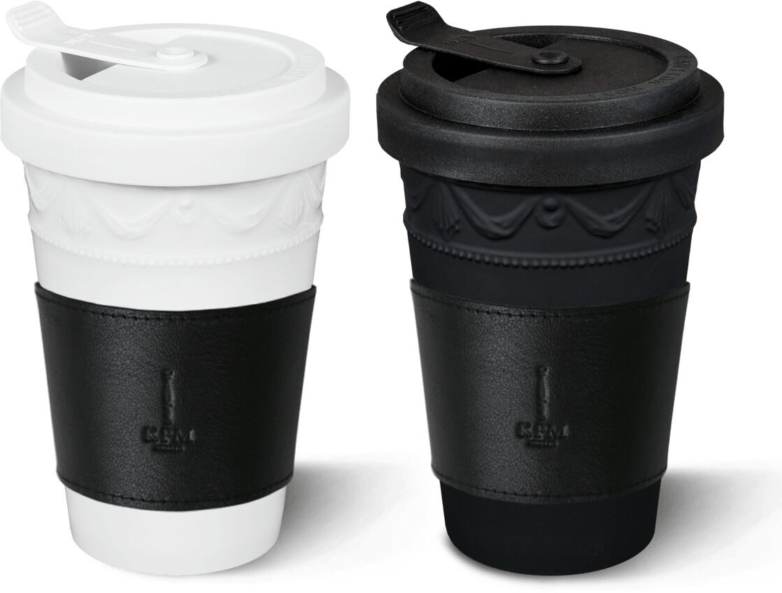 Zwei KPM Kurland to-go Becher aus Porzellan, einer in Weiß und einer in Schwarz, mit schwarzer Griffmanschette und Deckel.