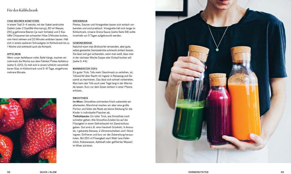 Eine Frau hält drei Glasflaschen mit gesunden grünen und roten Säften. Daneben steht ein aufgeschlagenes Kochbuch mit Rezepten und einem Foto von Erdbeeren.