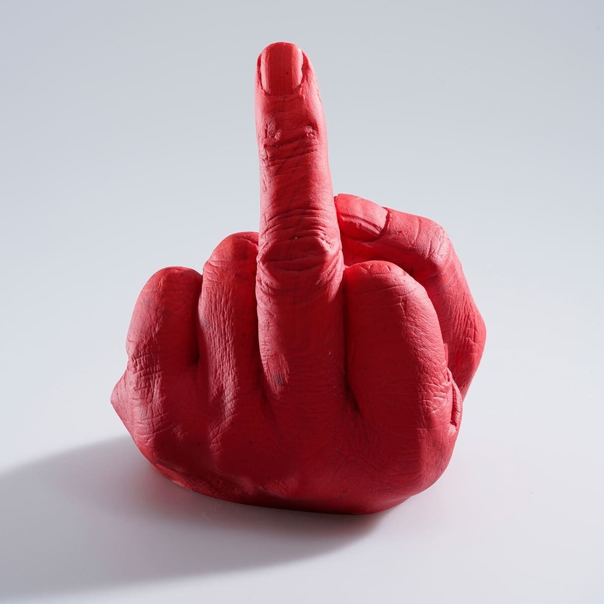 Dieses Bild zeigt eine rote Skulptur einer Hand, die den Mittelfinger zeigt. Das Kunstwerk stammt von Ai Weiwei und trägt den Titel »Study of Perspective in Glass«.