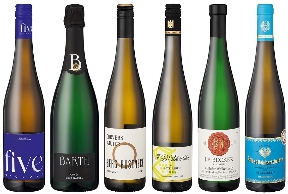 Sechs verschiedene Weinflaschen der ZEIT-Weinedition »Rheingau«, von links nach rechts: eine weiße Flasche mit blauem Etikett, eine dunkle Flasche mit schwarzem Etikett, eine weiße Flasche mit weißen Etikett und schwarzem Text, eine Flasche mit grünem Etikett, eine Flasche mit weißem Etikett und rotem Siegel und eine Flasche mit türkisem Etikett. Alle Flaschen haben unterschiedliche Etiketten-Designs.