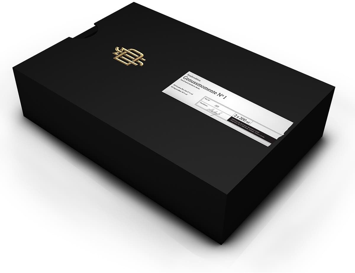 Schwarze elegante Schachtel der ZEIT-Sonderedition „Genussmomente No 1“ mit einem goldenen Logo und einem weißen Etikett mit schwarzem Text.