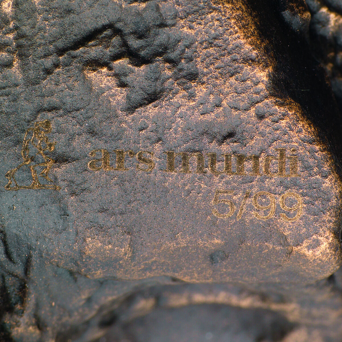 Eine Bronzeskulptur mit dunklen Brauntönen und goldenen Details. In die Oberfläche ist die Aufschrift 'ars mundi 57/99' eingraviert. Die Skulptur ist ein künstlerisches Werk von Christoph Fischer mit dem Titel 'Der Gedanke'.