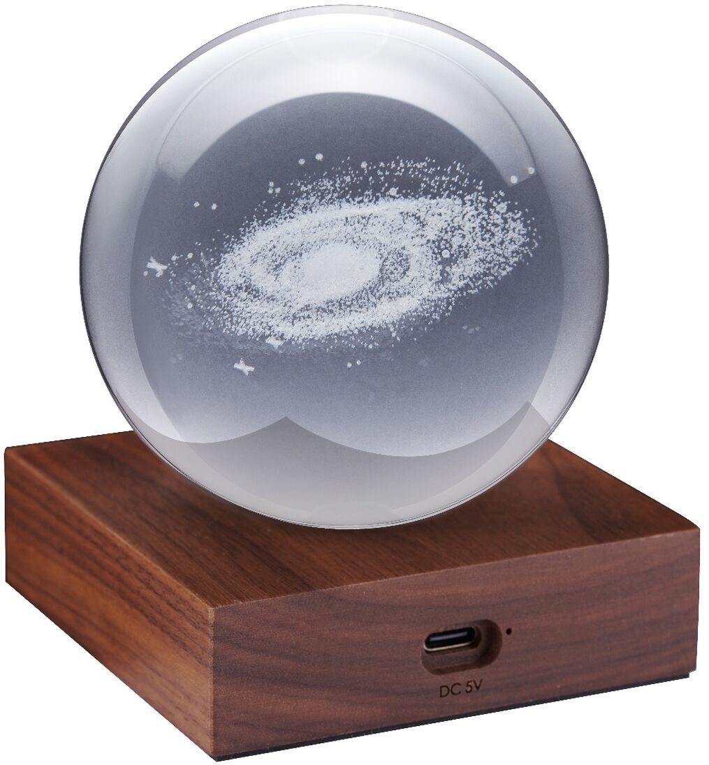 Produktfoto einer Lampe namens »Amber Light« mit einer runden, klaren Kristallkugel im Galaxiedesign auf einem rechteckigen Holzsockel. Die Lampe dient als dekorative Ambientebeleuchtung und stimmungsvoller Blickfang für verschiedene Wohnbereiche.