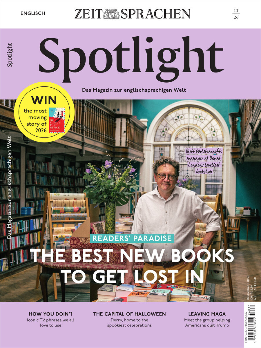 Titelblatt des Sprachmagazins „Spotlight“ von ZEIT SPRACHEN, Ausgabe 13/2026. In einer gemütlichen Buchhandlung steht ein Mann hinter einem Tisch voller Bücher; hohe Regale, Blumen und ein großes Bogenfenster rahmen ihn. Titel: „The Best New Books to Get Lost In“. Gelber Gewinnspiel-Kreis und weitere Themenleisten auf lila Grund.