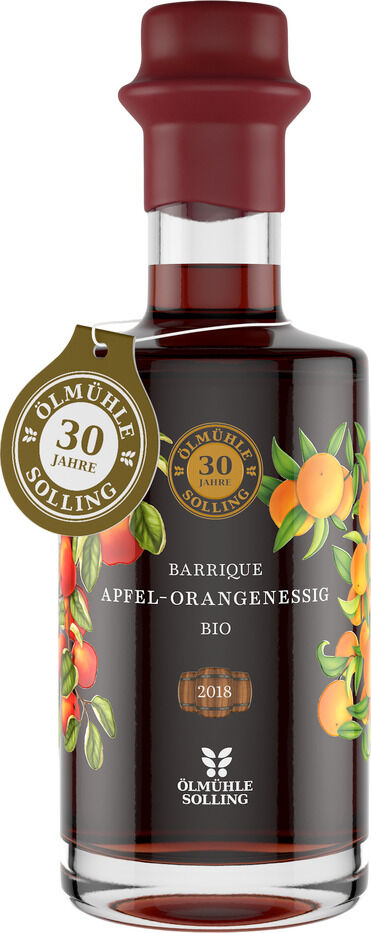 Flasche Barrique Apfel-Orange-Essig von Ölmühle Solling mit dekorativem Etikett, goldener Jubiläumsplakette und Früchtemotiven. Edle Glasflasche, braune Flüssigkeit, schwarze und goldene Schrift. Geeignet als Geschenk zu besonderen Anlässen.