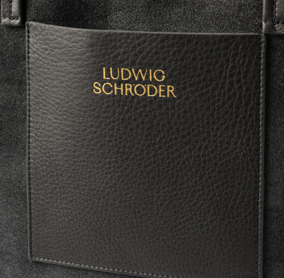 Nahaufnahme einer hochwertigen Ledertasche »Marie«, Abbildung zeigt das geprägte Logo 'Ludwig Schröder' auf einem rechteckigen schwarzen Lederpatch.