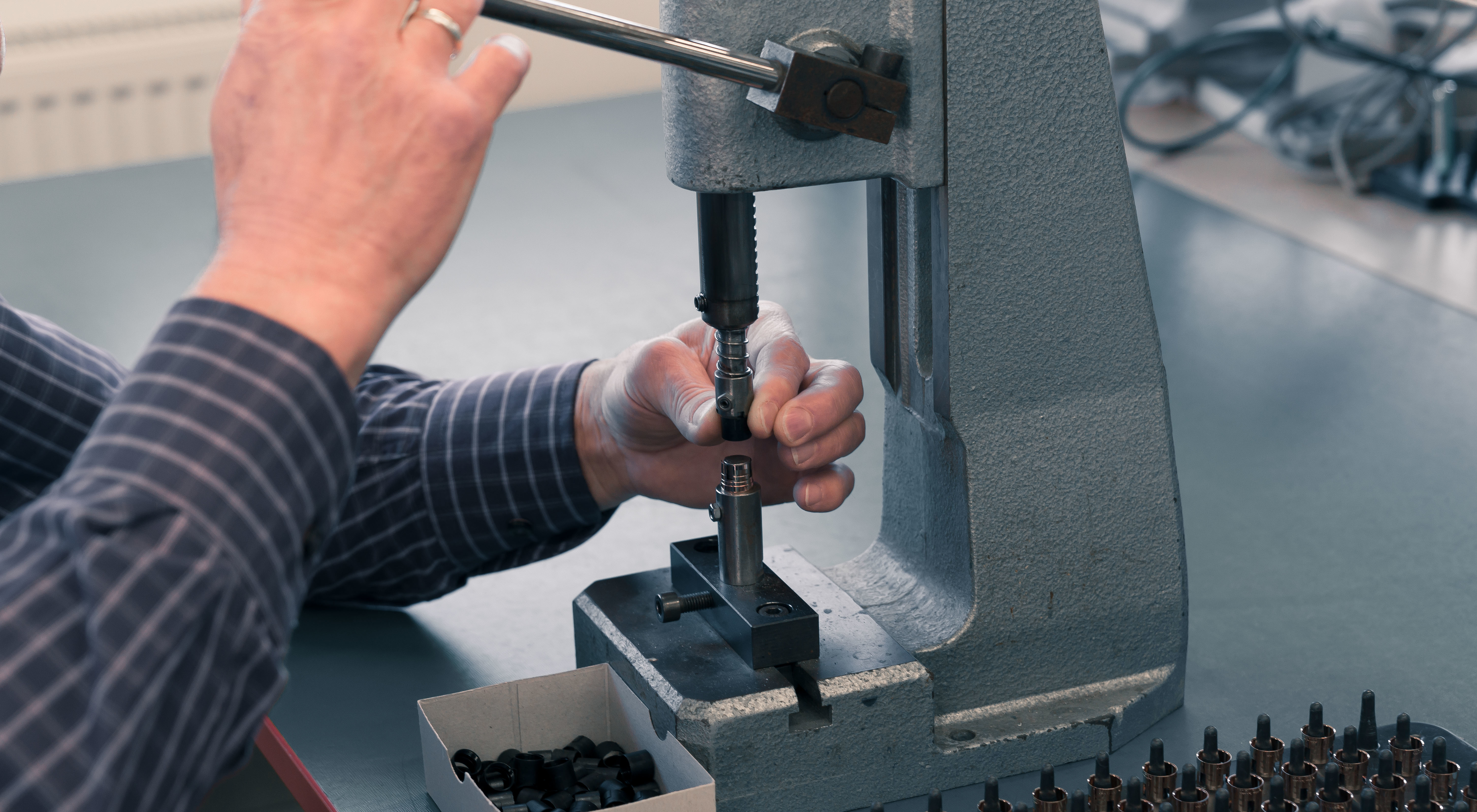 Hand bedient eine manuelle Presse zur Montage oder Prüfung von kleinen Metallteilen auf einem Tisch