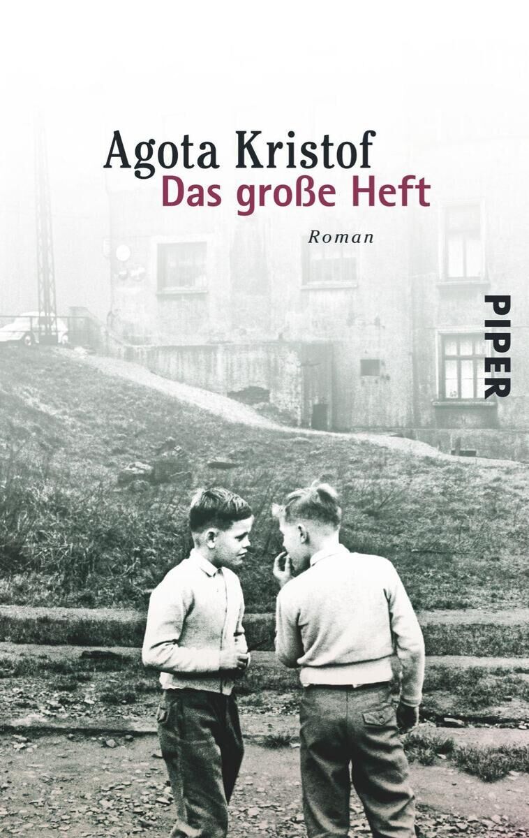 Das Cover des Buches 'Das große Heft' von Agota Kristof zeigt ein Schwarz-Weiß-Foto zweier Jungen, die auf einer Wiese sprechen. Im Hintergrund ist eine Art Wohngebäude zu sehen. Der Titel in roter Schrift und der Autorname darüber in schwarzer Schrift. Rechts am Rand steht das Wort 'Piper'.