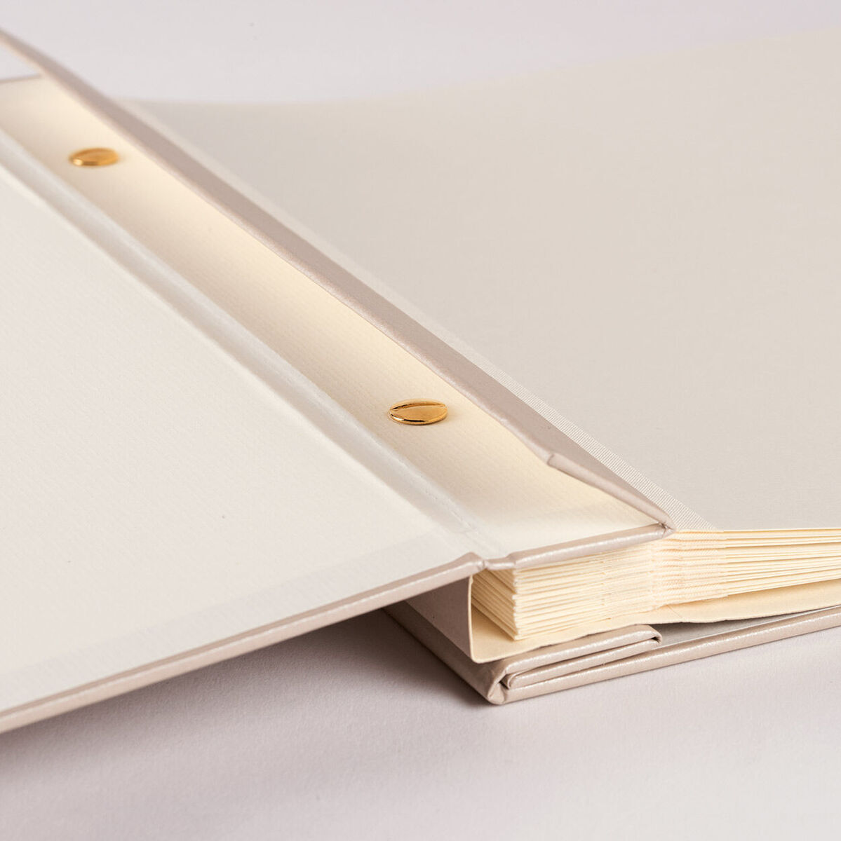 Ein Fotoalbum mit weißen und beige-farbenen Seiten sowie goldenen Befestigungsschrauben, perfekt zum Aufbewahren von wertvollen Erinnerungen.