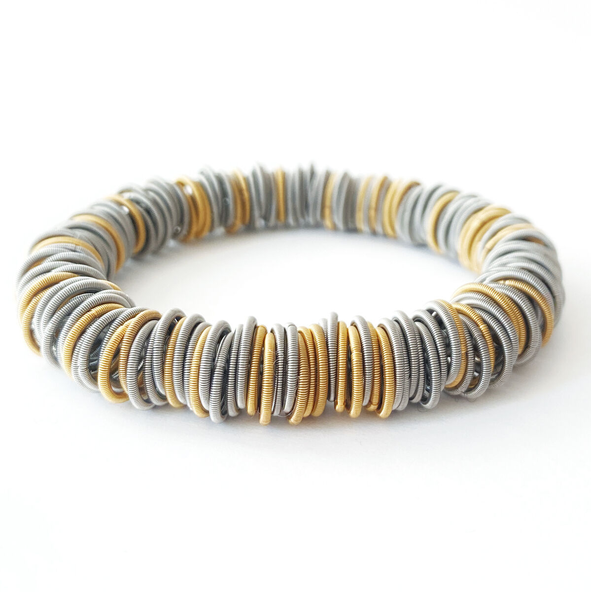 Elastisches Armband bestehend aus kleinen, goldenen und silbernen Ringen, die aufgereiht eine stilvolle und modische Optik ergeben. Geeignet für Herren und Damen als Accessoire.