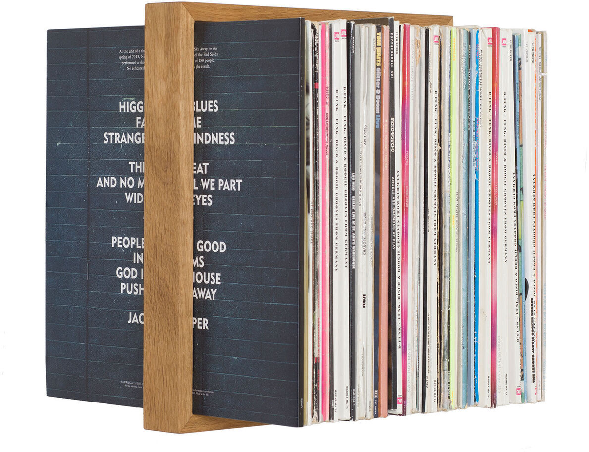 Ein moderner Plattenständer aus Holz mit mehreren Schallplatten darin. Der Plattenständer hat eine minimalistische und stilvolle Gestaltung, und die Platten sind ordentlich nach Farbe und Design sortiert.