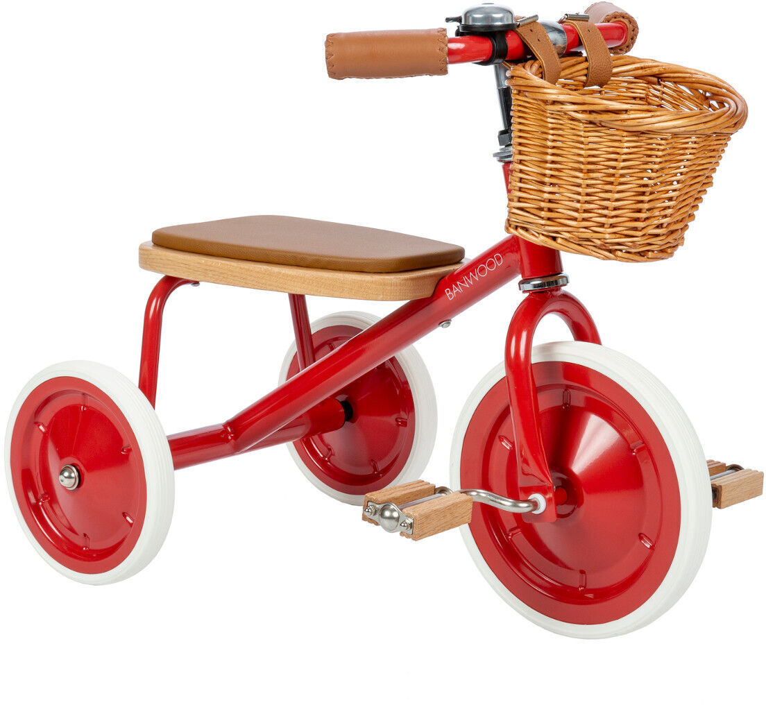 Ein Retro-Dreirad mit rotem Rahmen, weißen Rädern und Holzpedalen. Das Dreirad hat einen braunen Sitz und einen Wicker Korb am Lenker.