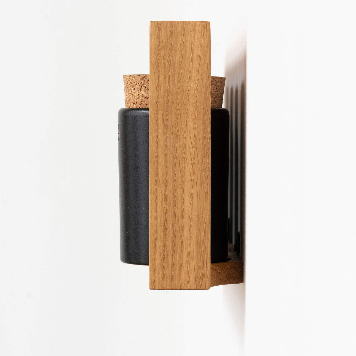 Ein Gewürzregal der Marke »bocuse«, das an einer weißen Wand befestigt ist. Das Regal besteht aus hellem Holz und beherbergt schwarze Gewürzbehälter mit Korkverschlüssen.
