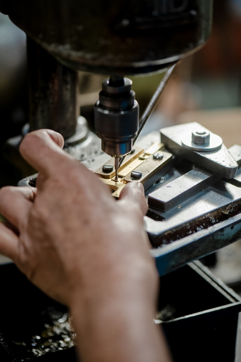 Eine Nahaufnahme einer Hand, die eine Außwetterstation der ZEIT-Sonderedition an einer Werkbank montiert. Feinmechanische Arbeiten mit einer Bohrmaschine werden gezeigt.
