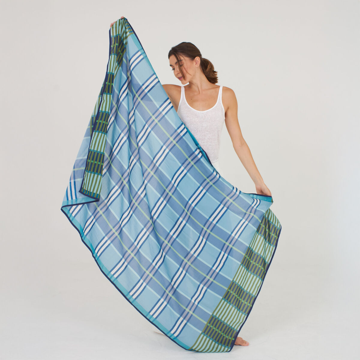 Ein elegant drapierter Baumwoll-Seidenschal "Morgan" der Marke Shalls Barcelona liegt in Falten auf einem hellen Untergrund. Das Tuch zeigt verschiedene Blautöne mit weißem Muster, wirkt leicht und hochwertig. Die feine Webung verleiht ihm einen seidigen Glanz.