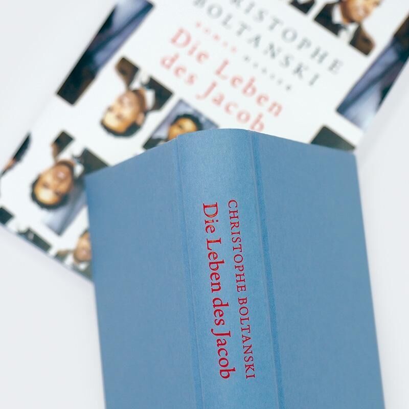 Das Bild zeigt das Buch 'Die Leben des Jacob' von Christophe Boltanski. Das Buch hat einen blauen Einband mit roter Schrift und liegt auf einem Hintergrund, der das Buchcover mit mehreren Bildausschnitten zeigt.