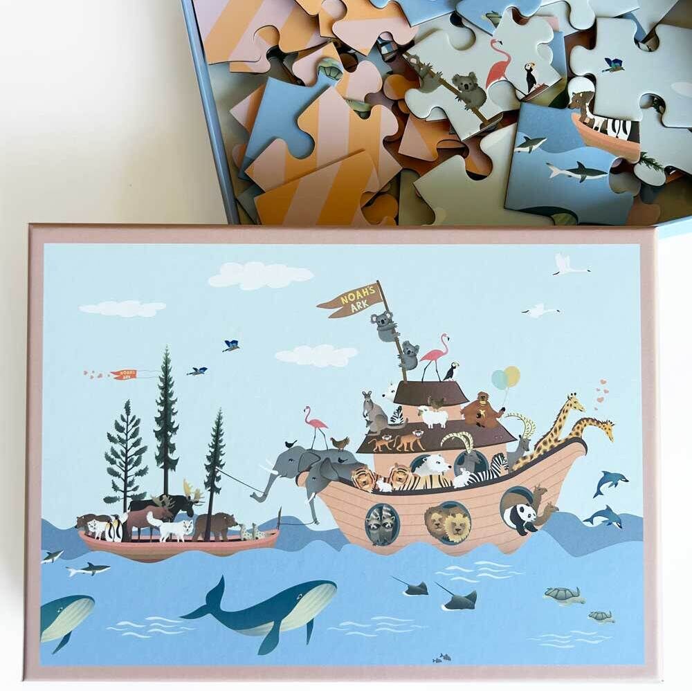 Puzzle »Noahs Arche« mit einer farbenfrohen Illustration von Tieren, die auf einer Arche fahren, umgeben vom Meer und blauem Himmel. Das Puzzle ist teilweise zusammengesetzt in einer offenen Schachtel.