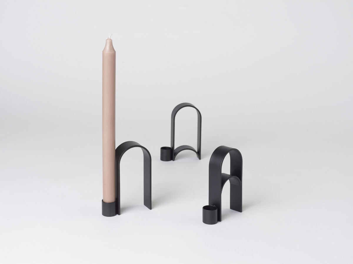 Ein modernes Design-Kerzenhalter-Set aus Metall namens 'Arch' Vol.10 in Schwarz. Der Kerzenhalter verfügt über einen eleganten und minimalistischen Bogenstil. Eine beige Kerze ist in einem der Kerzenhalter platziert. Geeignet für eine Vielzahl von Anlässen, insbesondere als stilvolle Inneneinrichtung.