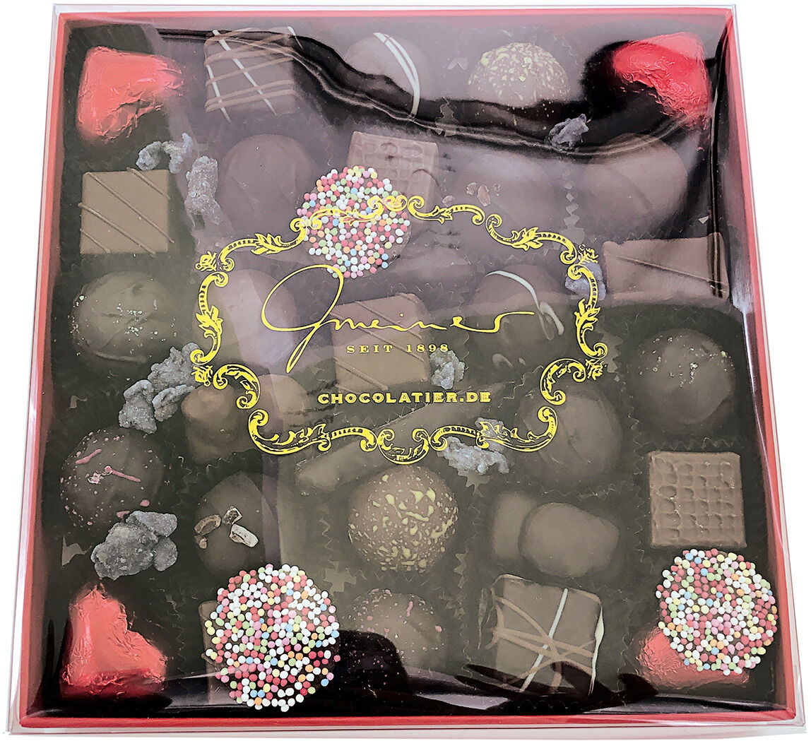 Eine Schachtel mit verschiedenen handgemachten Pralinen, die in einer eleganten Verpackung präsentiert werden.