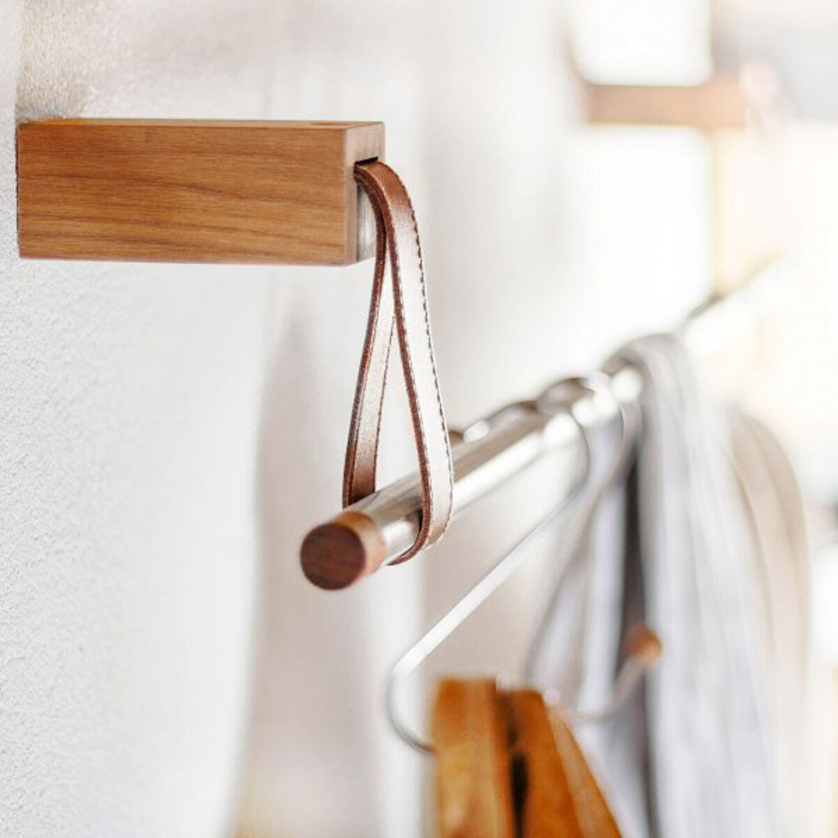 Holzkleiderhaken der Garderobe »Ansa« aus Eiche, montiert an einer weißen Wand, mit daran hängendem Kleiderbügel.