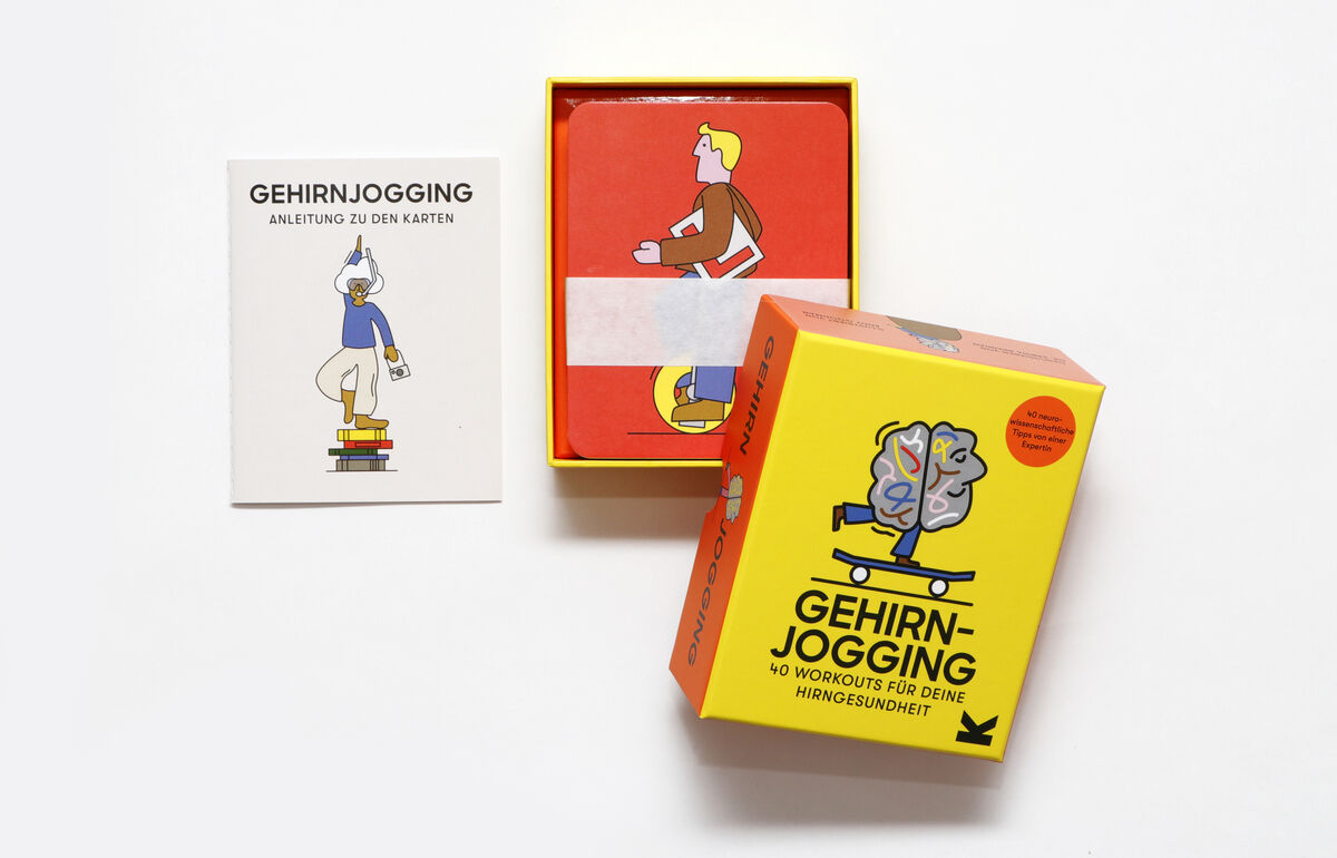 Das Bild zeigt das Gedächtnisspiel »Gehirnjogging« bestehend aus einer gelben Box mit den Worten 'Gehirnjogging – 40 Workouts für deine Hirnzellen', Spielkarten und einer Anleitung. Die Spielkarten sind rot, und auf der Anleitung ist eine illustrierte Figur, die auf Büchern balanciert.