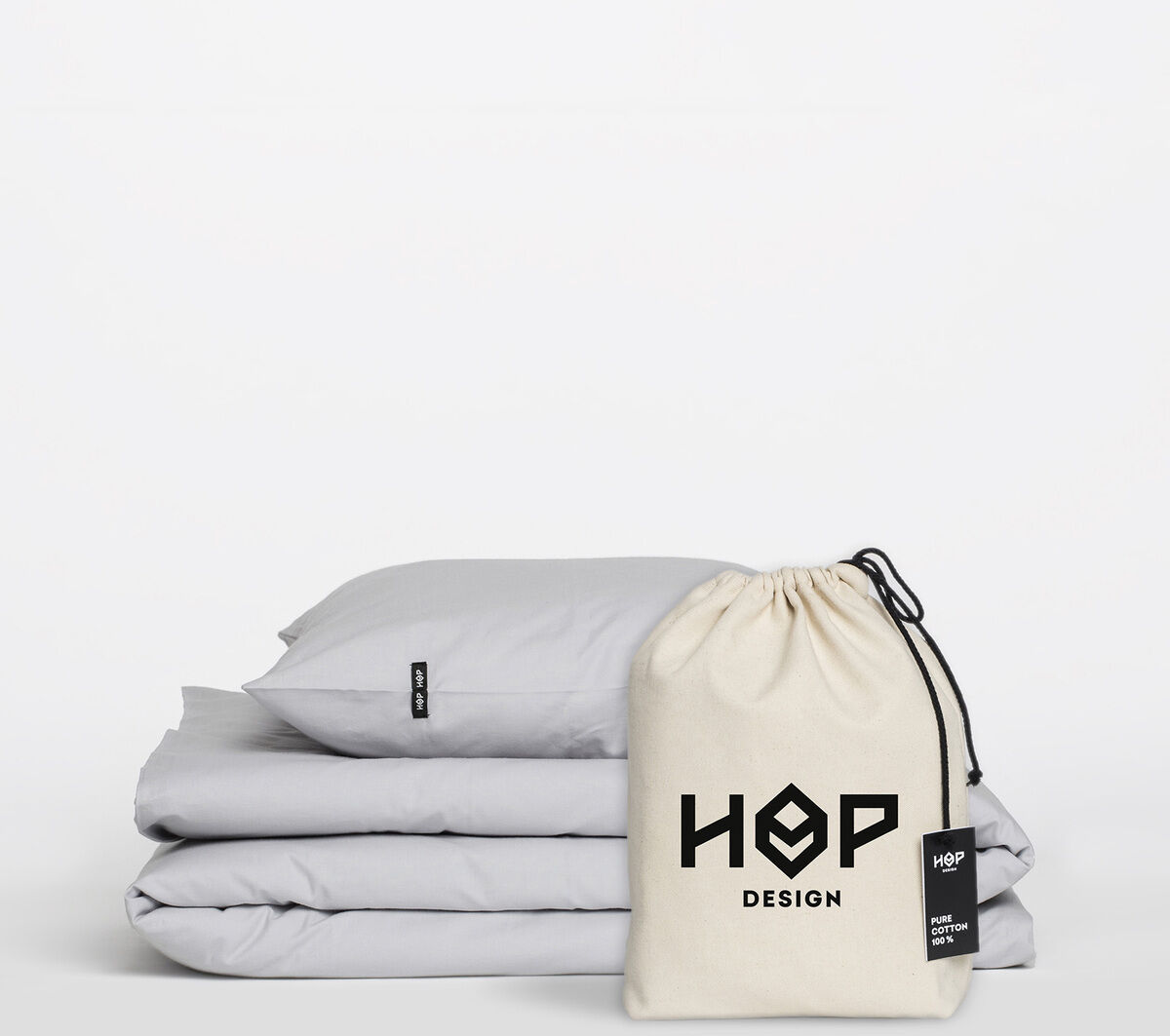 Ein Set aus grauer Bettwäsche von HOP Design mit minimalistischem Stil. Die Bettwäsche besteht aus weicher Baumwolle und wird in einem cremefarbenen Beutel präsentiert.