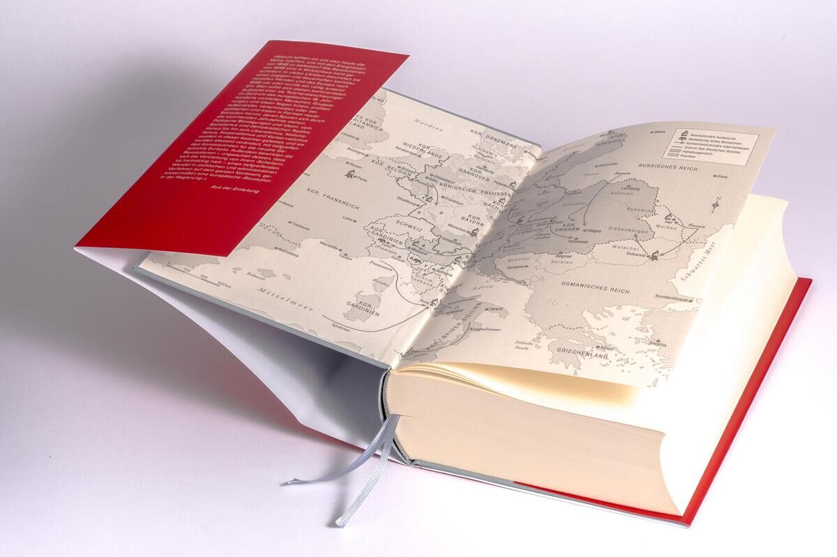 Ein aufgeschlagenes Buch mit rotem Einband und historischem Kartenmaterial. Der Titel des Buches lautet 'Clark, C: Frühling der Revolution'.
