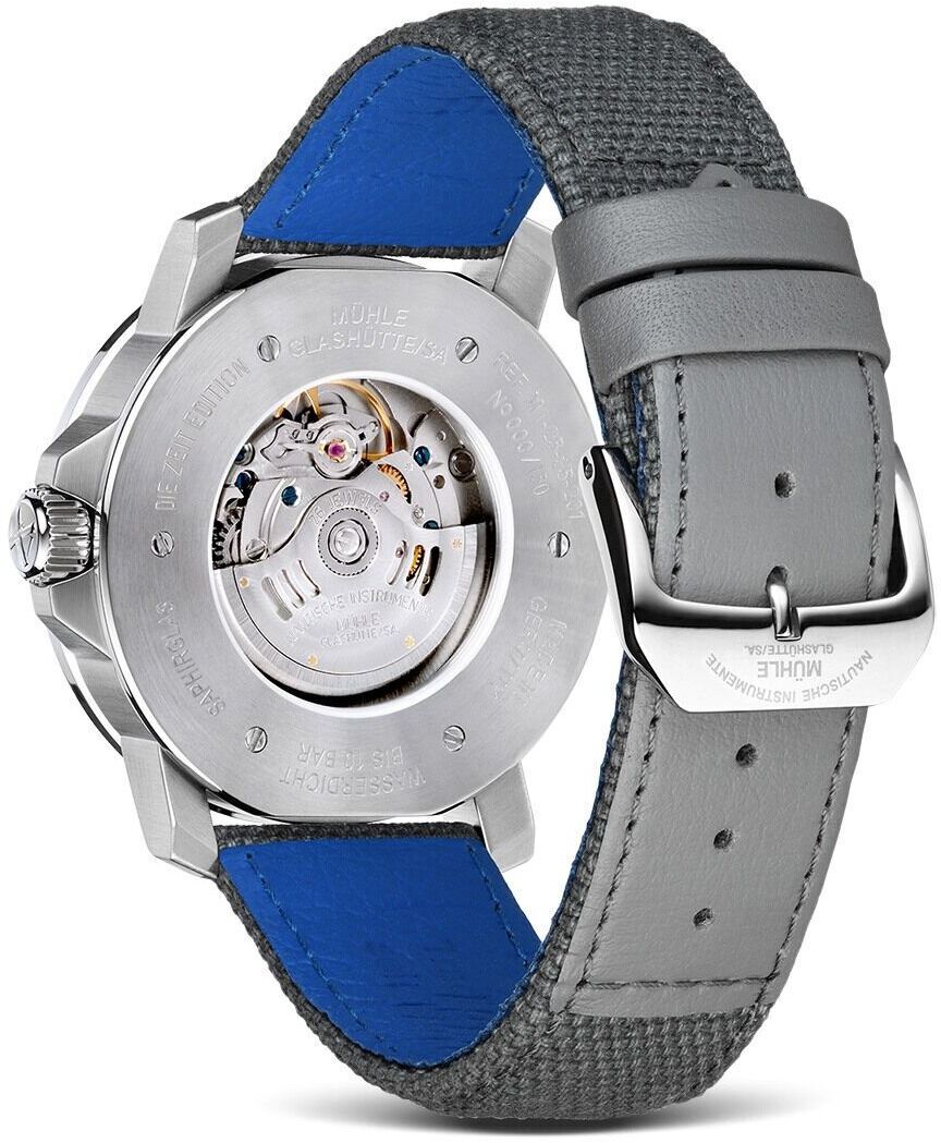 Die Rückseite der ZEIT-Sonderedition »29er Big« (2019) von Mühle-Glashütte zeigt ein mechanisches Uhrwerk mit einem silbernen Edelstahlgehäuse und einem grauen Lederarmband mit blauer Innenseite.