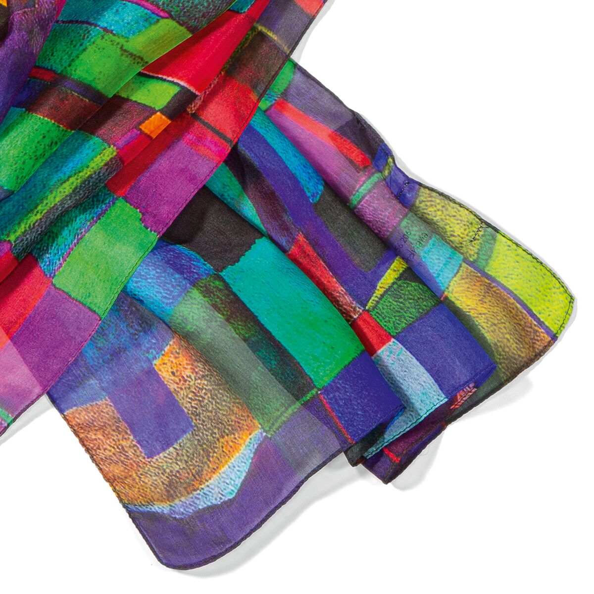 Auf dem Bild ist der Seidenschal »Estelle« der Marke Ars mundi zu sehen. Der Schal zeigt ein lebendiges, künstlerisches Muster aus geometrischen Farbflächen in intensivem Grün, Blau, Rot, Gelb, Lila und Türkis. Die edle Seide glänzt, die Textur wirkt transparent und fein, das Format ist großzügig.