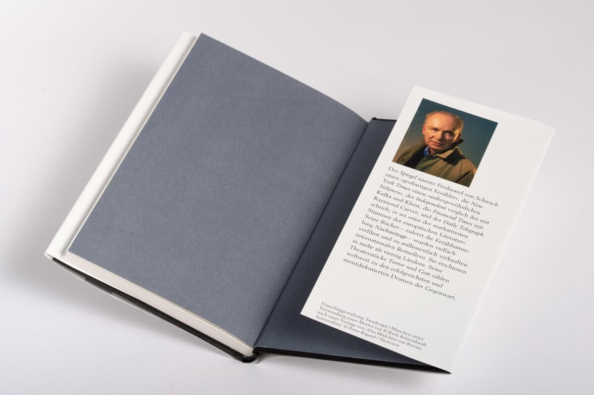 Das Bild zeigt das aufgeklappte Buch 'Regen' von Ferdinand von Schirach. Der Hintergrund ist weiß, und auf der rechten Seite des Buches befindet sich ein Autorfoto sowie ein Textabschnitt. Das Buch hat einen blauen Einband.