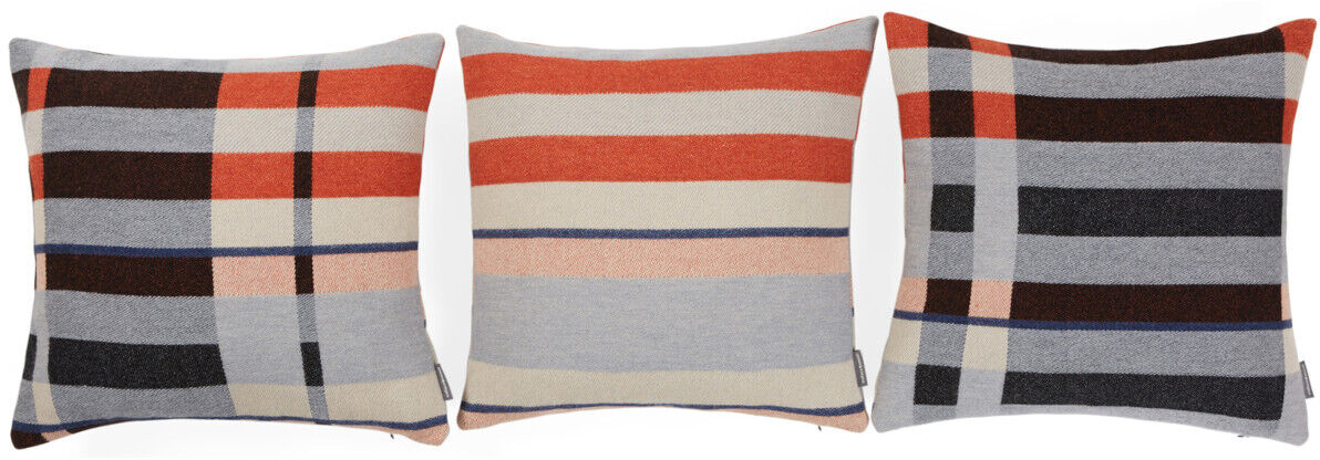 Drei Kissen im Bauhausstil mit geometrischen Mustern in Rot, Schwarz, Beige, Grau und Blau. Jedes Kissen zeigt eine einzigartige Anordnung von Streifen und Blöcken.