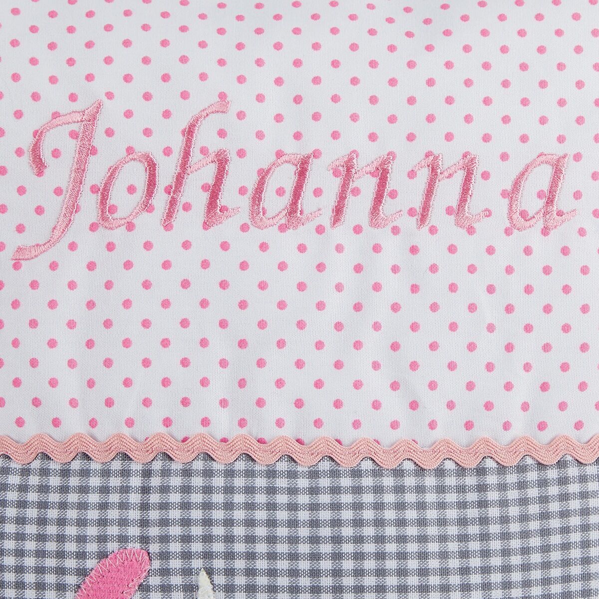 Ein personalisiertes Kissen mit dem Namen 'Johanna', gestaltet mit rosa Punkten auf weißem Hintergrund und einem grauen, karierten Muster unten; ideal für das Kinderzimmer.