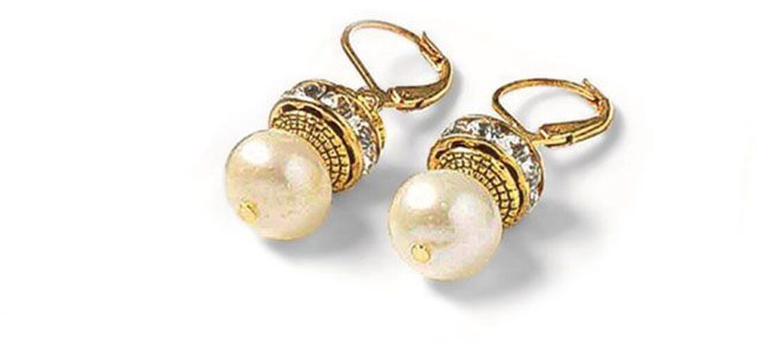 Ein Paar goldene Ohrringe mit großen weißen Perlen und feinen Verzierungen, designt von Petra Waszak.
