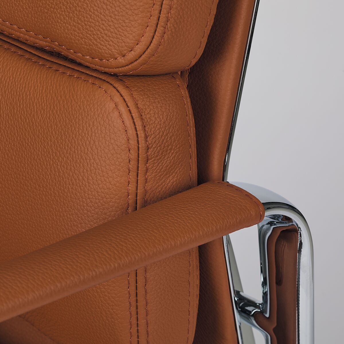 Detailaufnahme des ZEIT-Sonderedition Vitra Soft Pad EA217 Stuhls, der mit braunem Leder und silbernen metallischen Akzenten gestaltet ist.