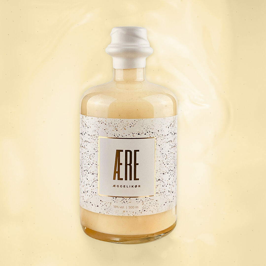 Flasche Aere Eierlikör vor einem cremefarbenen Hintergrund. Das Etikett der Flasche ist beige und gold mit feinen schwarzen Punkten.