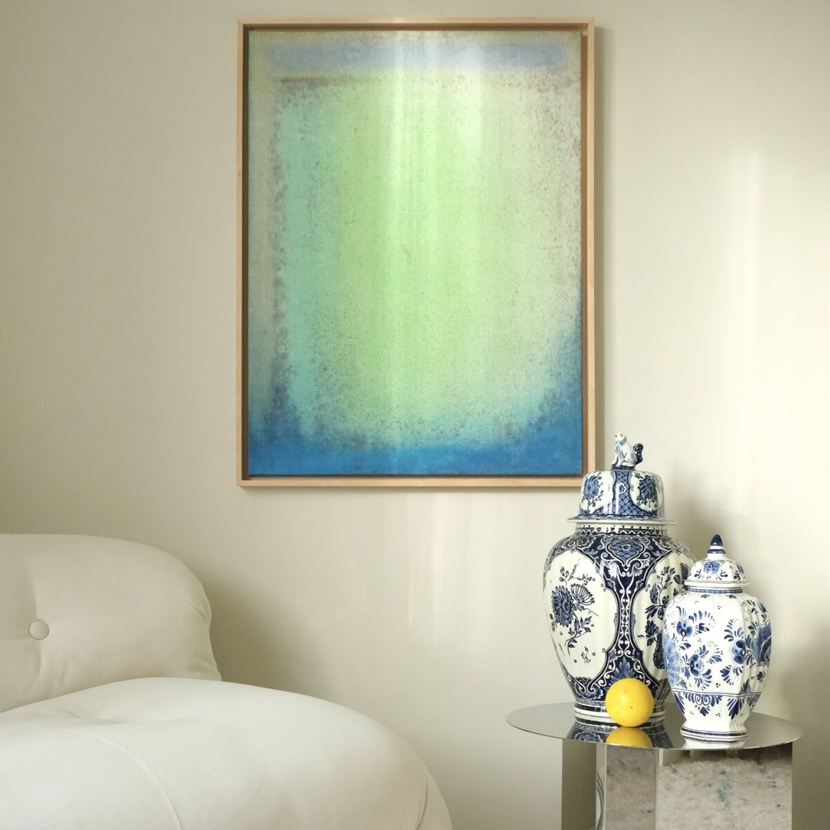 Ein moderner Kunstdruck im Format 80x60cm mit dem Titel »SORBET DECONSTRUCTED« hängt an einer beigen Wand. Darunter steht ein Beistelltisch mit zwei weißen, blau gemusterten Vasen und eine dritte größere Vase. Daneben steht ein weißes Sofa auf einem gemusterten Teppich.