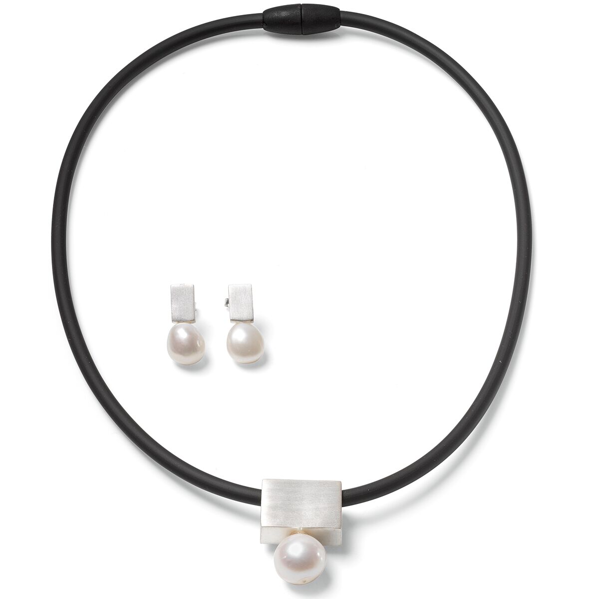 Das Bild zeigt das Schmuckset "Mother of Pearl" von Ars mundi: eine schwarze Kautschukkette mit einem rechteckigen, versilberten Anhänger und runder weißer Perle, dazu passende Ohrringe mit silbernem Stecker und hängender weißer Perle. Das Design ist elegant und modern.