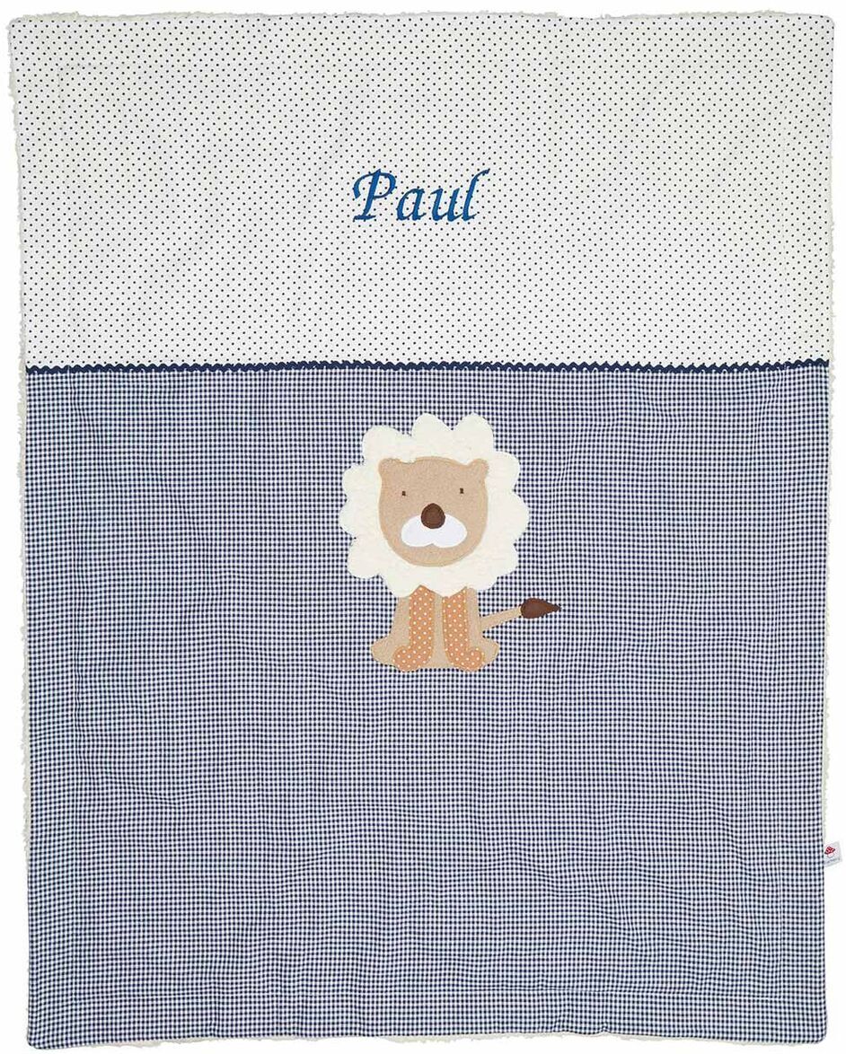 Eine Baby-Kuscheldecke mit einem gestickten Löwenmotiv und dem Namen 'Paul' auf einem weißen und blauen, gemusterten Hintergrund.