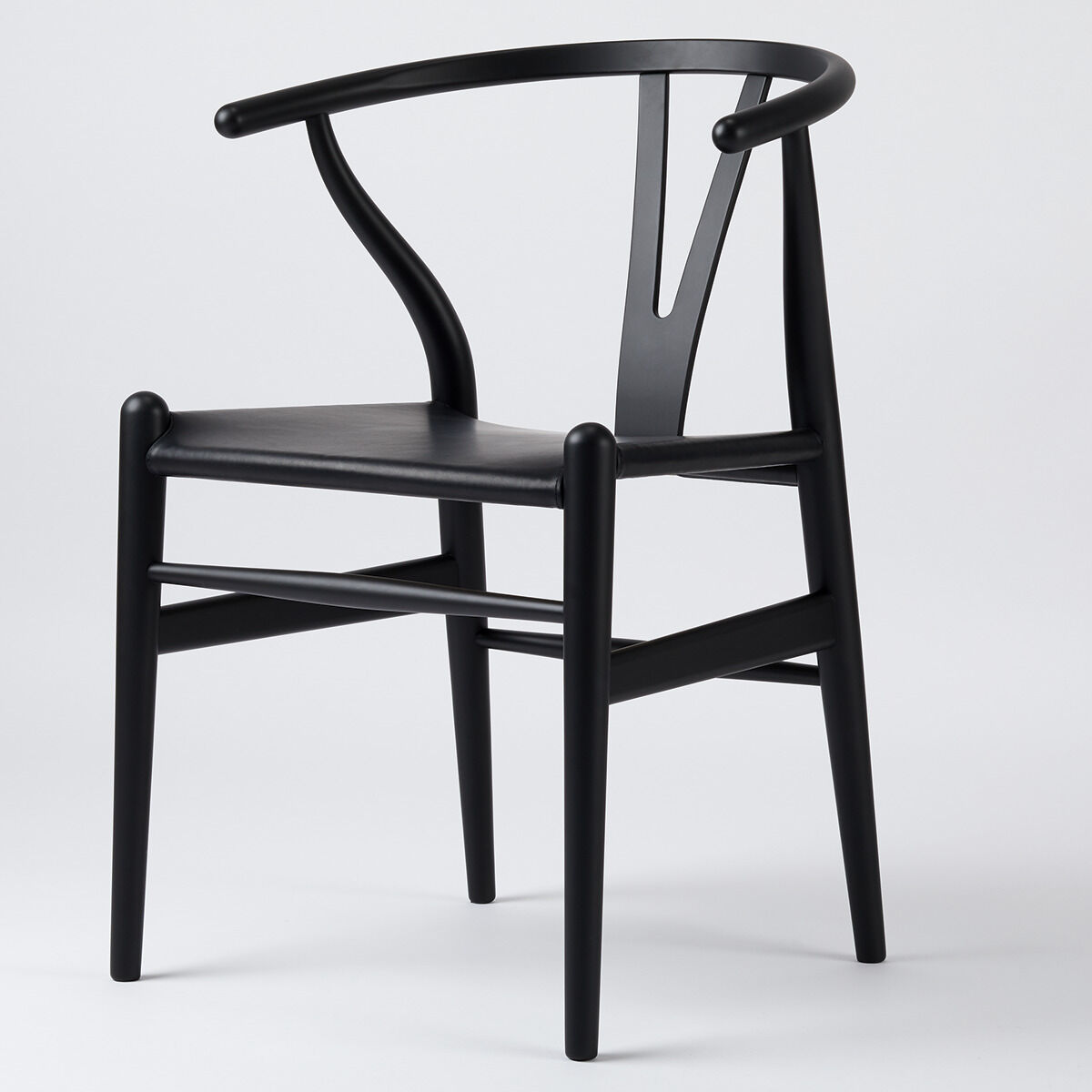 Ein eleganter, schwarzer Stuhl aus der ZEIT Sonderedition »CH24«, bekannt als Wishbone Chair, bestehend aus Buchenholz und einem Lederbezug, zeigt ein minimalistisches und skandinavisches Design.