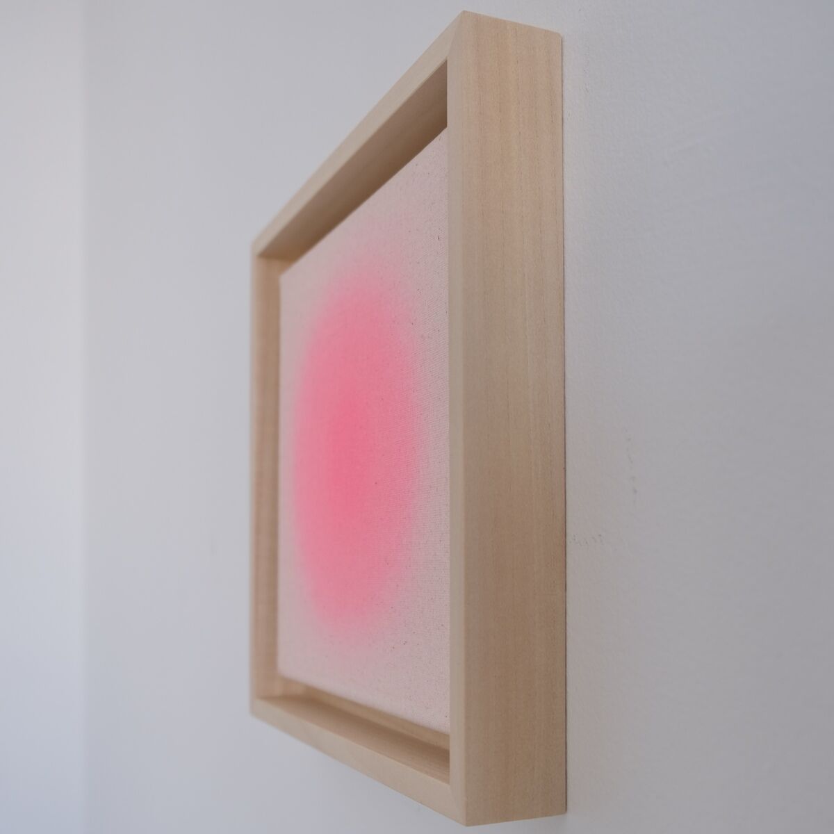 Das Bild zeigt das Kunstwerk ZEIT-Sonderedition Sorbet »Pink« in der Größe 20x20 cm. Zu sehen ist ein minimalistisches Wandbild mit einem hellen Holzrahmen und einem rosafarbenen, nach außen weich verlaufenden Farbpunkt auf weißem Hintergrund. Das Kunstwerk hängt an einer weißen Wand und verbreitet ein modernes, ruhiges Ambiente.