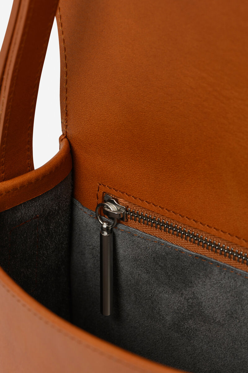Nahaufnahme einer braunen Ledertasche mit Reißverschlussfach aus grauem Stoff.