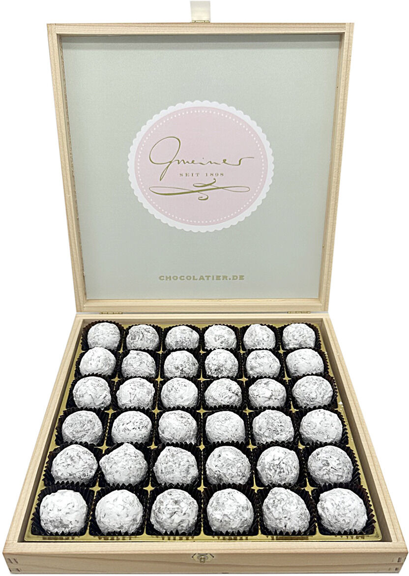 Elegante Holzbox mit 36 Champagnertrüffeln von Gmeiner. Die Pralinen sind mit weißem Puder bestäubt und einzeln in goldenen Papierförmchen angeordnet. Im Deckel der Box erscheint das Gmeiner-Logo auf mintgrünem Hintergrund. Hochwertiges Präsent für Genießer.