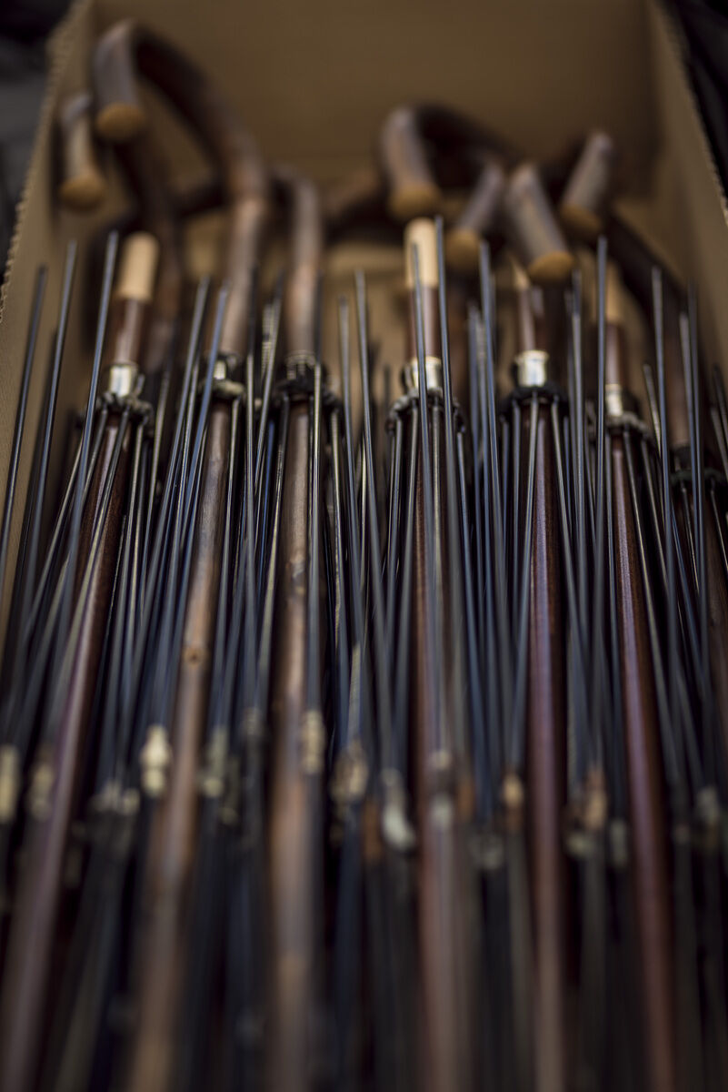 Mehrere edle Regenschirme mit braunen Holzgriffen und schwarzem Schaft stehen aufrecht in einer Box. Sie wirken hochwertig und stilvoll, perfekt für elegante Anlässe und als modisches Accessoire.