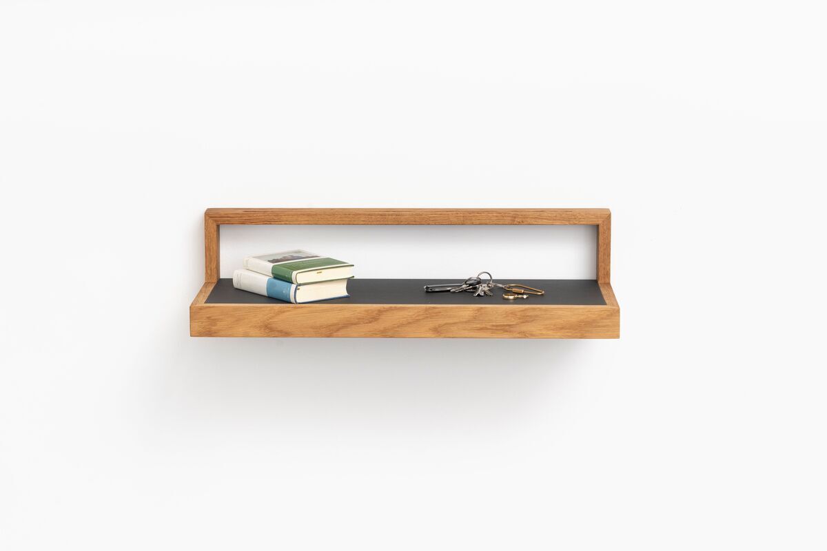 Ein Ablagebord in der Farbe Anthrazit mit einer Einfassung aus hellem Holz ist an einer weißen Wand montiert. Auf dem Bord liegen zwei Bücher und ein Schlüsselbund.