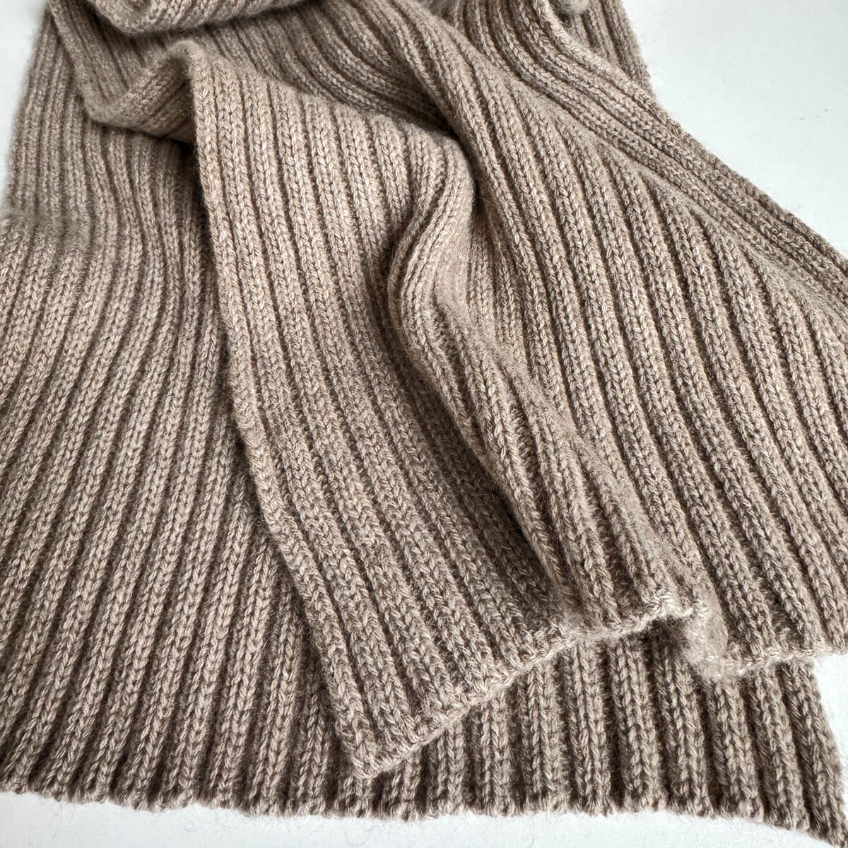 Großer, gerippter Schal aus naturbraunem Kaschmir der Marke Eagle Products liegt weich gefaltet auf hellem Untergrund. Die Struktur ist flauschig und grob gestrickt, das Material wirkt luxuriös und wärmend. Perfekt für stilbewusste Damen und Herren im Winter.
