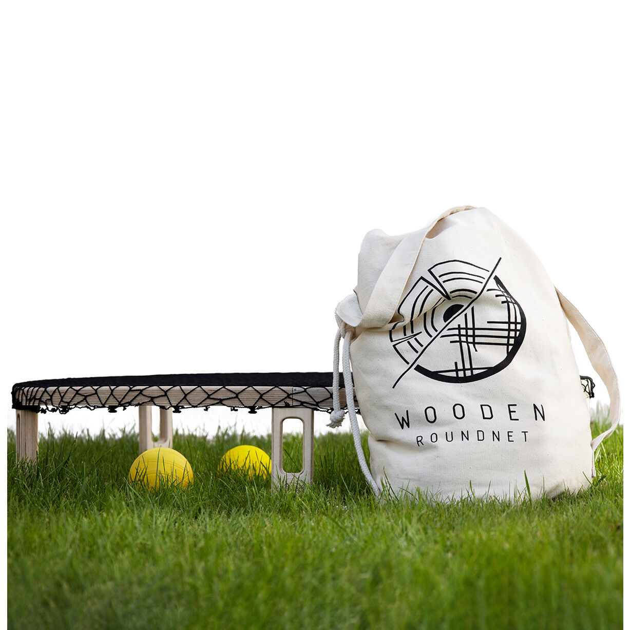 Ein Wooden Roundnet Set bestehend aus einem runden Netz auf Holzfüßen, mehreren Bällen und einer weißen Tragetasche mit Logo, auf grünem Gras platziert.