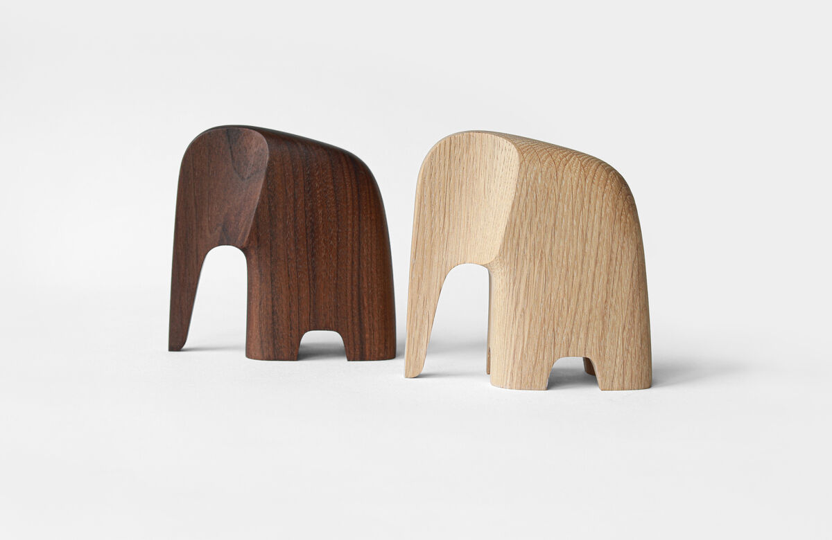 Zwei minimalistische Holzfiguren in Form von Elefanten aus Eichenholz, eine in brauner und die andere in naturfarbener Ausführung, auf einem weißen Hintergrund.