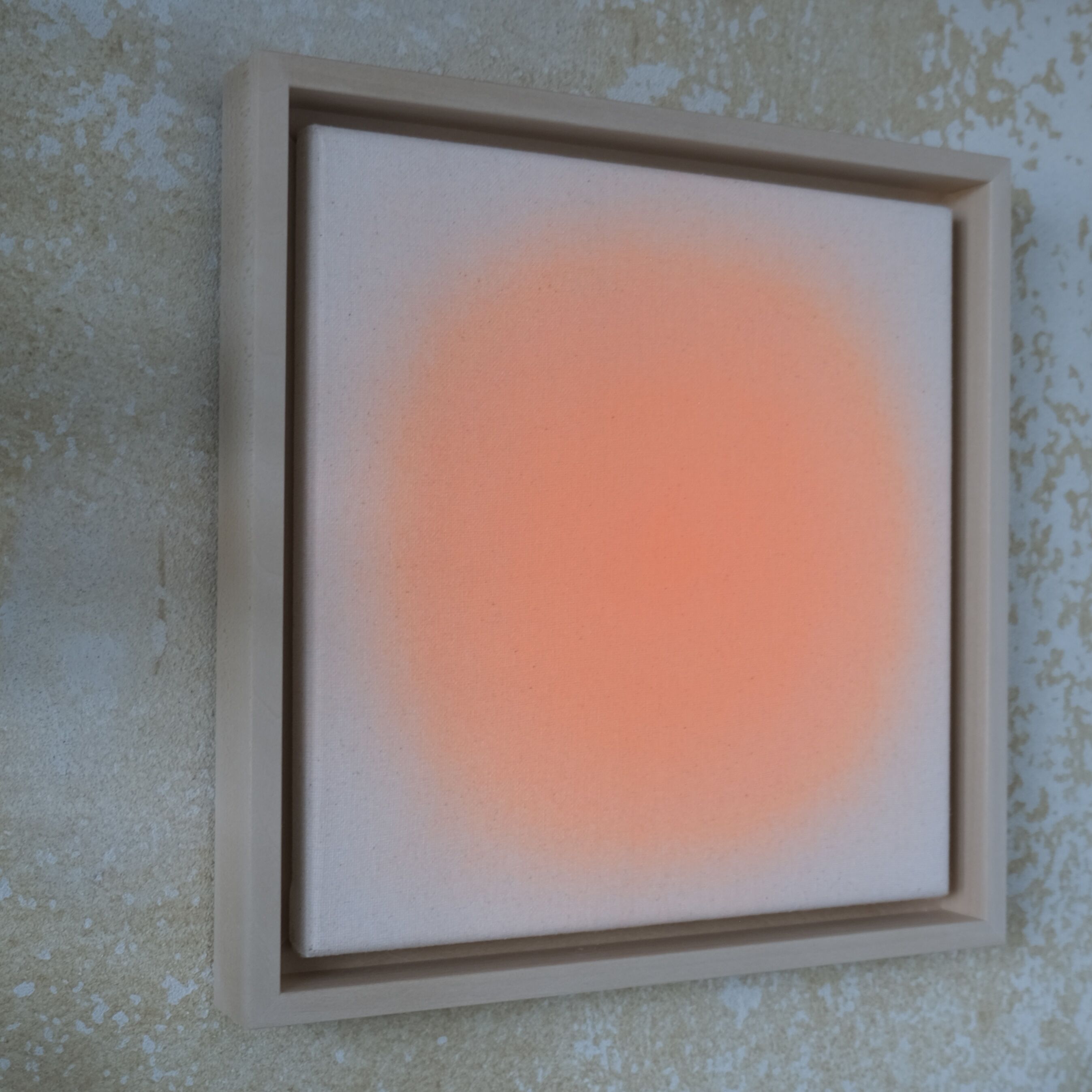 Quadratisches Kunstwerk von Anastasia Benko in zartem Orange auf ungrundierter Leinwand, von über 70 Farbschichten geprägt. In einem hellen Lindenholzrahmen an strukturiert-beiger Wand, sanft leuchtend und exklusiv für DIE ZEIT geschaffen.